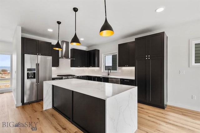 kitchen featuring appliances with stainless steel finishes, wall chimney range hood, a sink, plenty of natural light, and recessed lighting