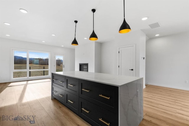 kitchen featuring light wood-style floors, pendant lighting, dark cabinetry, baseboards, and recessed lighting