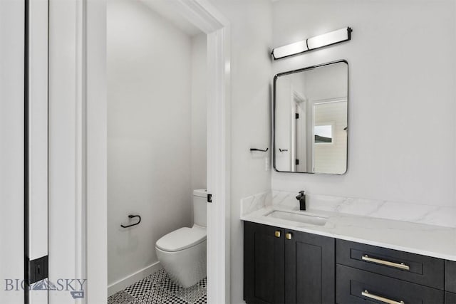 bathroom with toilet, vanity, baseboards, and tile patterned floors