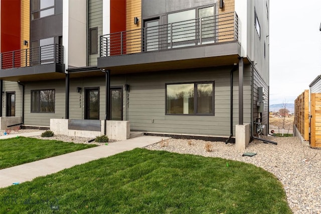 back of property featuring a balcony and a yard