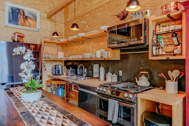 1007 E Geyser, Livingston, MT 59047 - kitchen featuring appliances with stainless steel finishes, butcher block countertops, a sink, backsplash, and hanging light fixtures