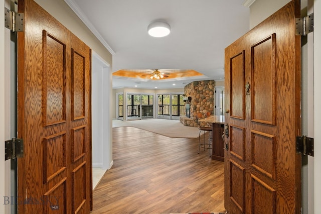 corridor with light wood-style flooring and crown molding