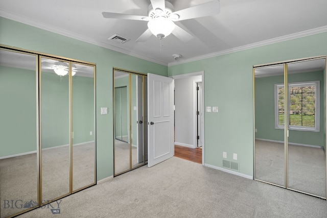 unfurnished bedroom featuring multiple closets, carpet flooring, crown molding, baseboards, and ceiling fan