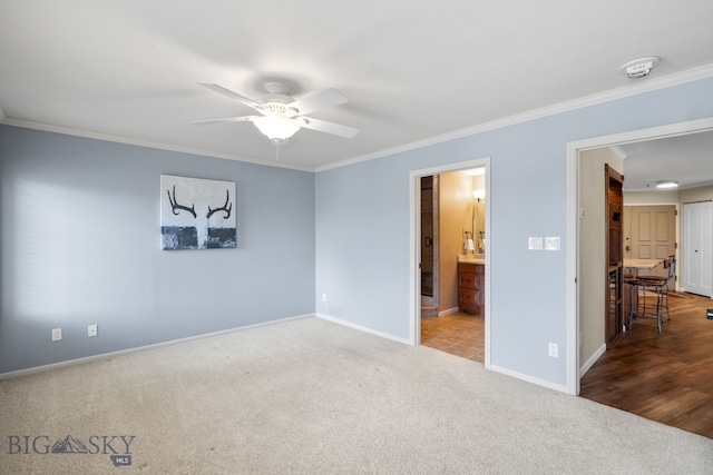 unfurnished bedroom featuring carpet, ornamental molding, baseboards, ensuite bath, and ceiling fan