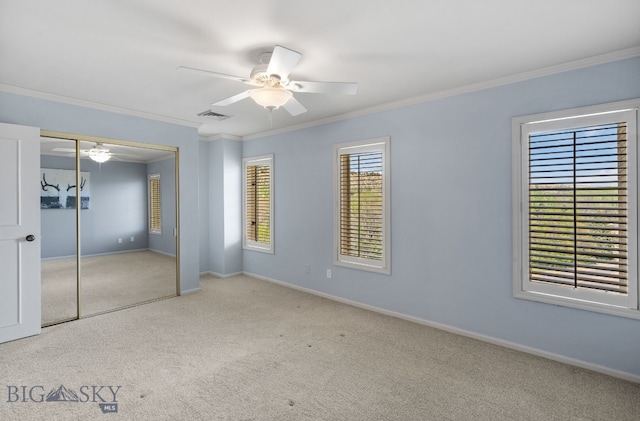 unfurnished bedroom featuring carpet flooring, crown molding, baseboards, a closet, and a ceiling fan