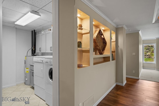 laundry room featuring independent washer and dryer, cabinet space, water heater, baseboards, and crown molding