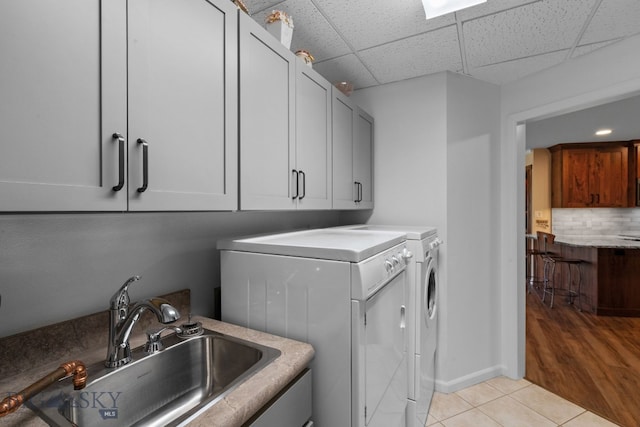 clothes washing area with washer and dryer, light tile patterned flooring, cabinet space, and baseboards