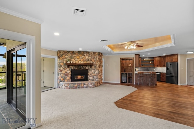 unfurnished living room featuring crown molding, a ceiling fan, a stone fireplace, recessed lighting, and carpet floors
