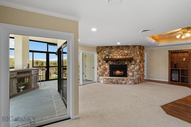 unfurnished living room featuring ornamental molding, a stone fireplace, baseboards, carpet floors, and recessed lighting