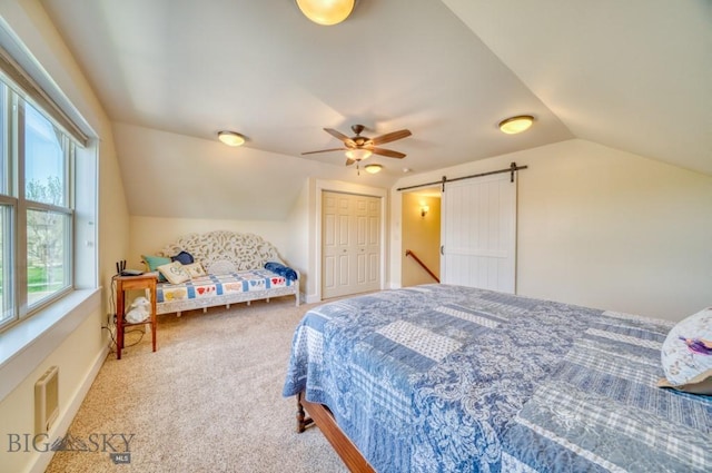 72 River Woods Rd, Belgrade, MT 59714 - carpeted bedroom with vaulted ceiling, a barn door, ceiling fan, and a closet