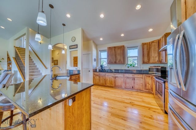 72 River Woods Rd, Belgrade, MT 59714 - kitchen featuring appliances with stainless steel finishes, a sink, pendant lighting, light wood finished floors, and a kitchen bar
