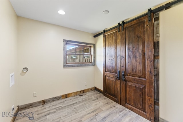 washroom with a barn door, light wood finished floors, hookup for a washing machine, baseboards, and recessed lighting