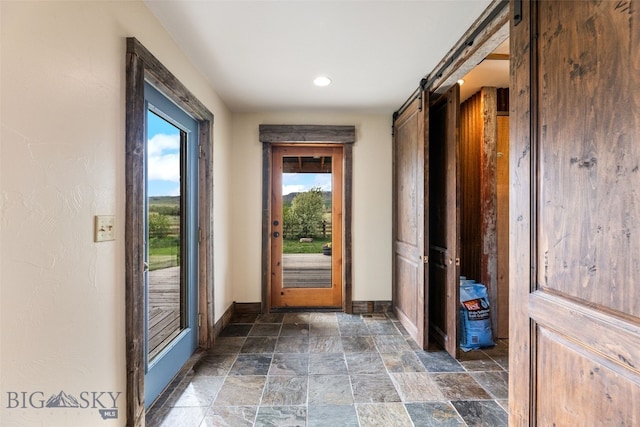 doorway with baseboards, dark stone finish floors, a barn door, and recessed lighting