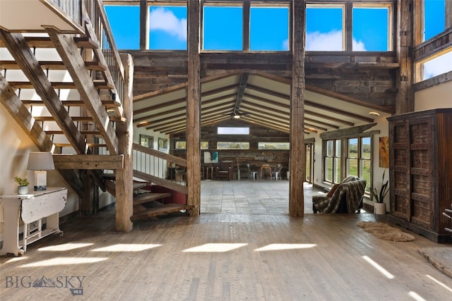 misc room featuring wood finished floors, stairway, and lofted ceiling