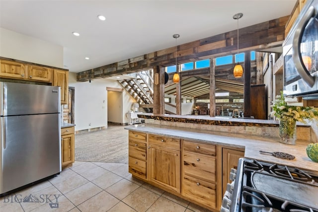 kitchen with appliances with stainless steel finishes, light countertops, recessed lighting, light tile patterned floors, and hanging light fixtures