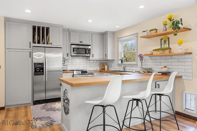 515 W Arnold St, Bozeman, MT 59715 - kitchen with butcher block counters, stainless steel appliances, open shelves, gray cabinetry, and a peninsula