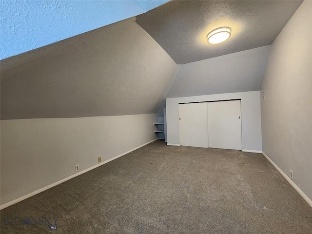 bonus room with a textured ceiling, lofted ceiling, carpet floors, and baseboards