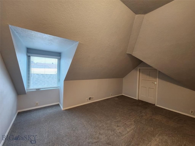 bonus room with vaulted ceiling, dark carpet, baseboards, and a textured ceiling