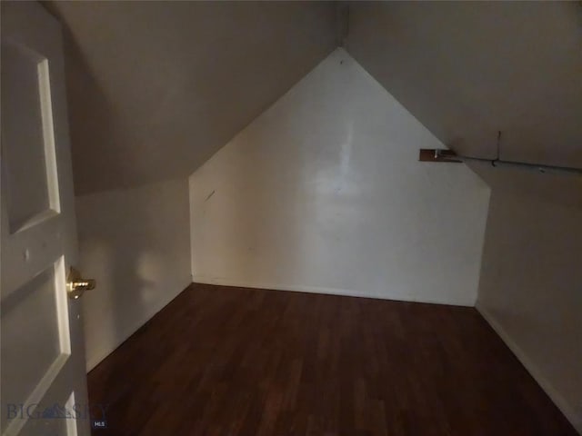 additional living space featuring vaulted ceiling, dark wood-type flooring, and baseboards