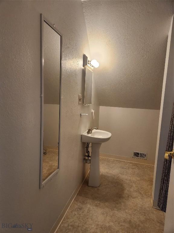 bathroom featuring a textured wall, a sink, and a textured ceiling