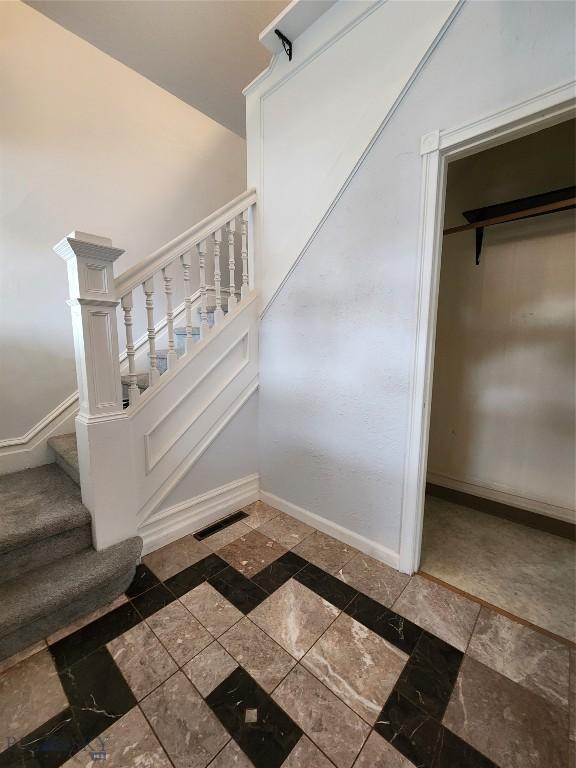 staircase featuring baseboards and inlaid floor details
