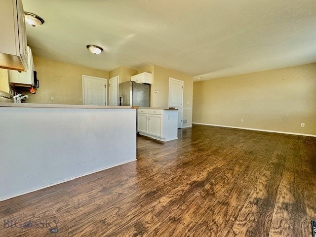 unfurnished living room featuring dark wood-style floors and baseboards