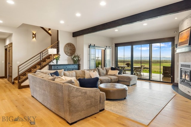 200 Miller Point Pl, Belgrade, MT 59714 - living room featuring beamed ceiling, stairs, recessed lighting, light wood-style floors, and a glass covered fireplace