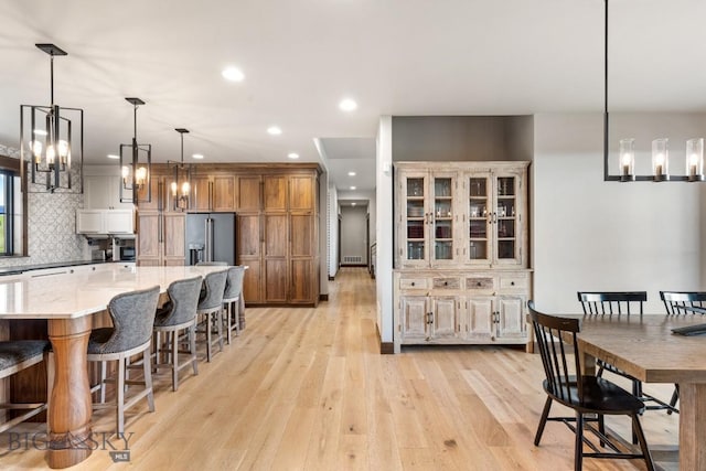 200 Miller Point Pl, Belgrade, MT 59714 - kitchen with high end refrigerator, light wood-style flooring, recessed lighting, a breakfast bar area, and tasteful backsplash