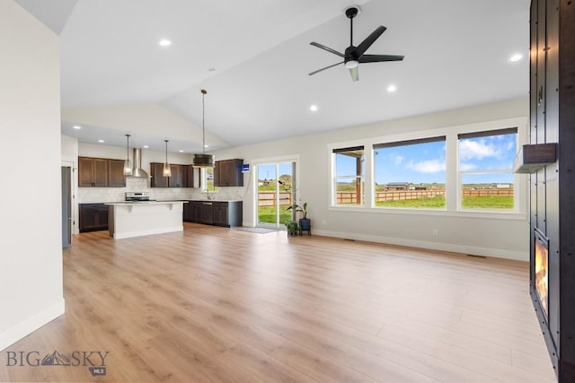 unfurnished living room with vaulted ceiling, recessed lighting, ceiling fan, a sink, and light wood-type flooring