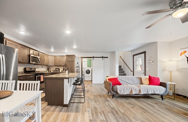 705 Halfpipe St Unit B, Belgrade, MT 59714 - kitchen with stainless steel appliances, washer / dryer, a kitchen breakfast bar, a barn door, and ceiling fan