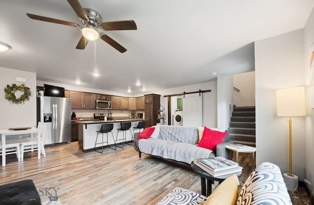 705 Halfpipe St Unit B, Belgrade, MT 59714 - living area with washer / dryer, ceiling fan, stairway, a barn door, and light wood finished floors