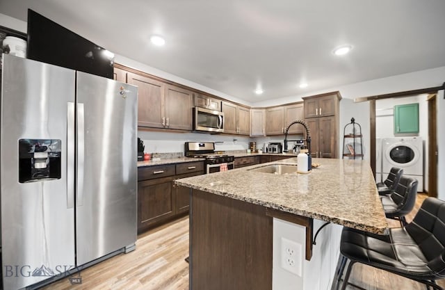 705 Halfpipe St Unit B, Belgrade, MT 59714 - kitchen with stainless steel appliances, washer / dryer, a sink, a breakfast bar, and light stone counters