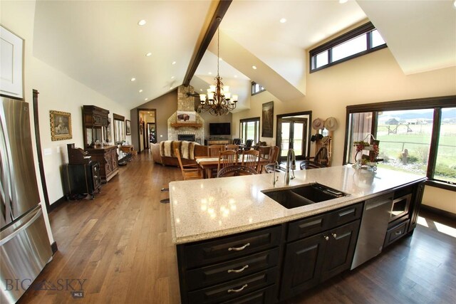 7 N Lewis And Clark Trl, Whitehall, MT 59759 - kitchen with stainless steel appliances, high vaulted ceiling, a chandelier, dark wood-type flooring, and an island with sink
