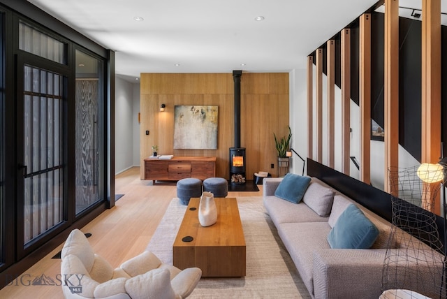 living area featuring light wood finished floors, a wood stove, and recessed lighting