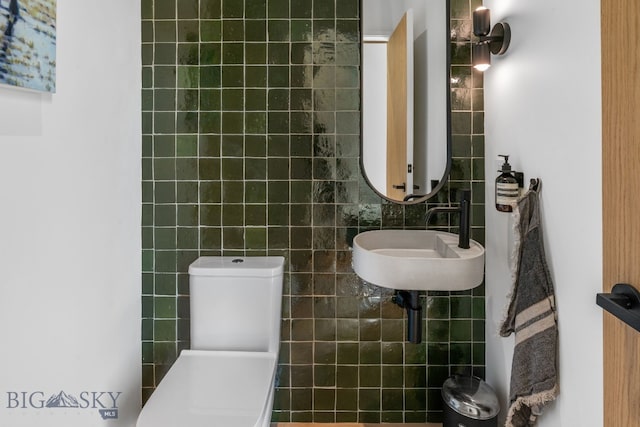 bathroom with tile walls, a sink, and toilet