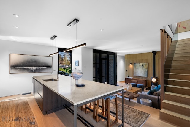 kitchen with a sink, light wood-style flooring, decorative light fixtures, light stone countertops, and recessed lighting