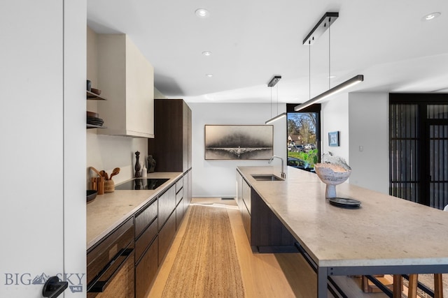 kitchen with modern cabinets, a sink, a large island with sink, recessed lighting, and decorative light fixtures