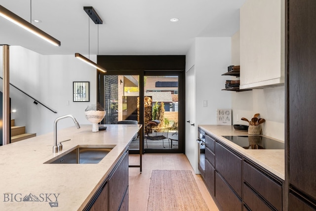 kitchen with a sink, black appliances, light countertops, dark brown cabinetry, and recessed lighting