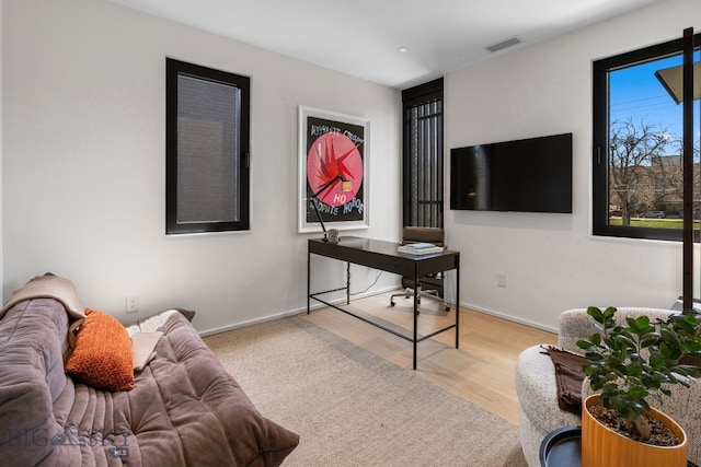 living room featuring wood finished floors, baseboards, and a desk