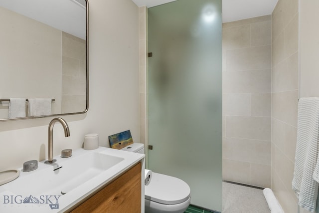 full bathroom featuring toilet, a tile shower, and vanity