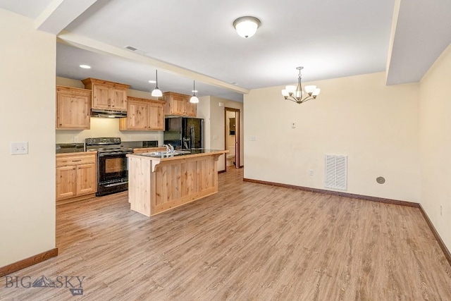 kitchen featuring black appliances, under cabinet range hood, baseboards, light brown cabinets, and a chandelier