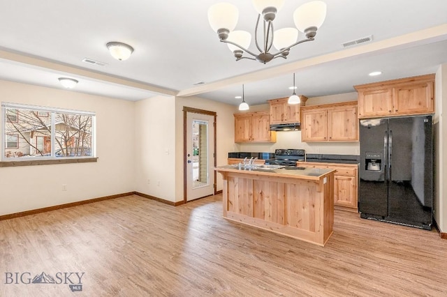 kitchen with black refrigerator with ice dispenser, light brown cabinetry, stove, under cabinet range hood, and light wood finished floors