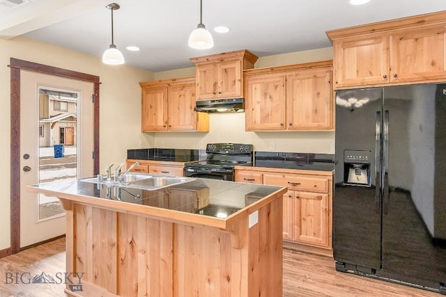 kitchen featuring black appliances, under cabinet range hood, light brown cabinetry, a sink, and recessed lighting