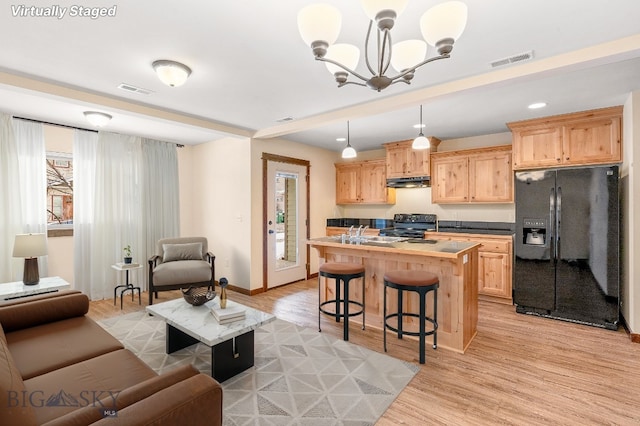 living area featuring light wood finished floors, a chandelier, and baseboards