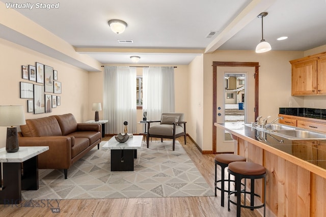 living area with light wood finished floors, baseboards, and beamed ceiling