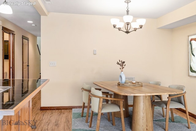dining area featuring a chandelier, baseboards, and wood finished floors