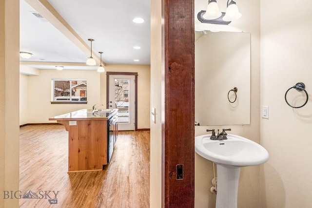 bathroom with wood finished floors, a sink, baseboards, and recessed lighting