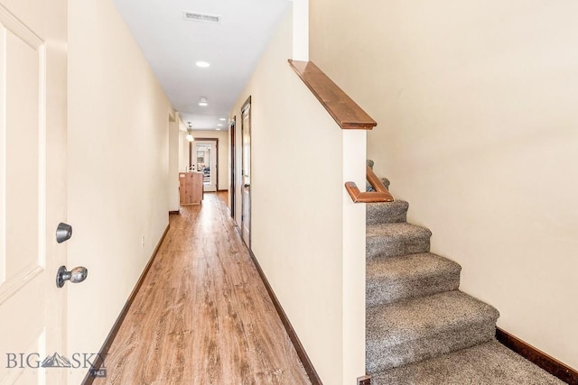 corridor featuring stairs, light wood-type flooring, baseboards, and recessed lighting