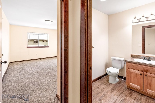 bathroom featuring toilet, vanity, baseboards, and wood finished floors