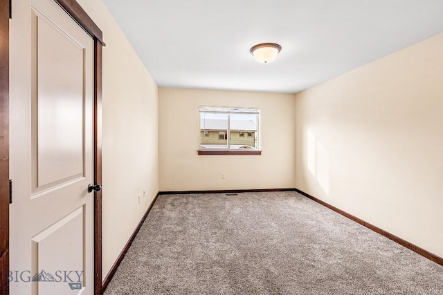 carpeted empty room featuring baseboards